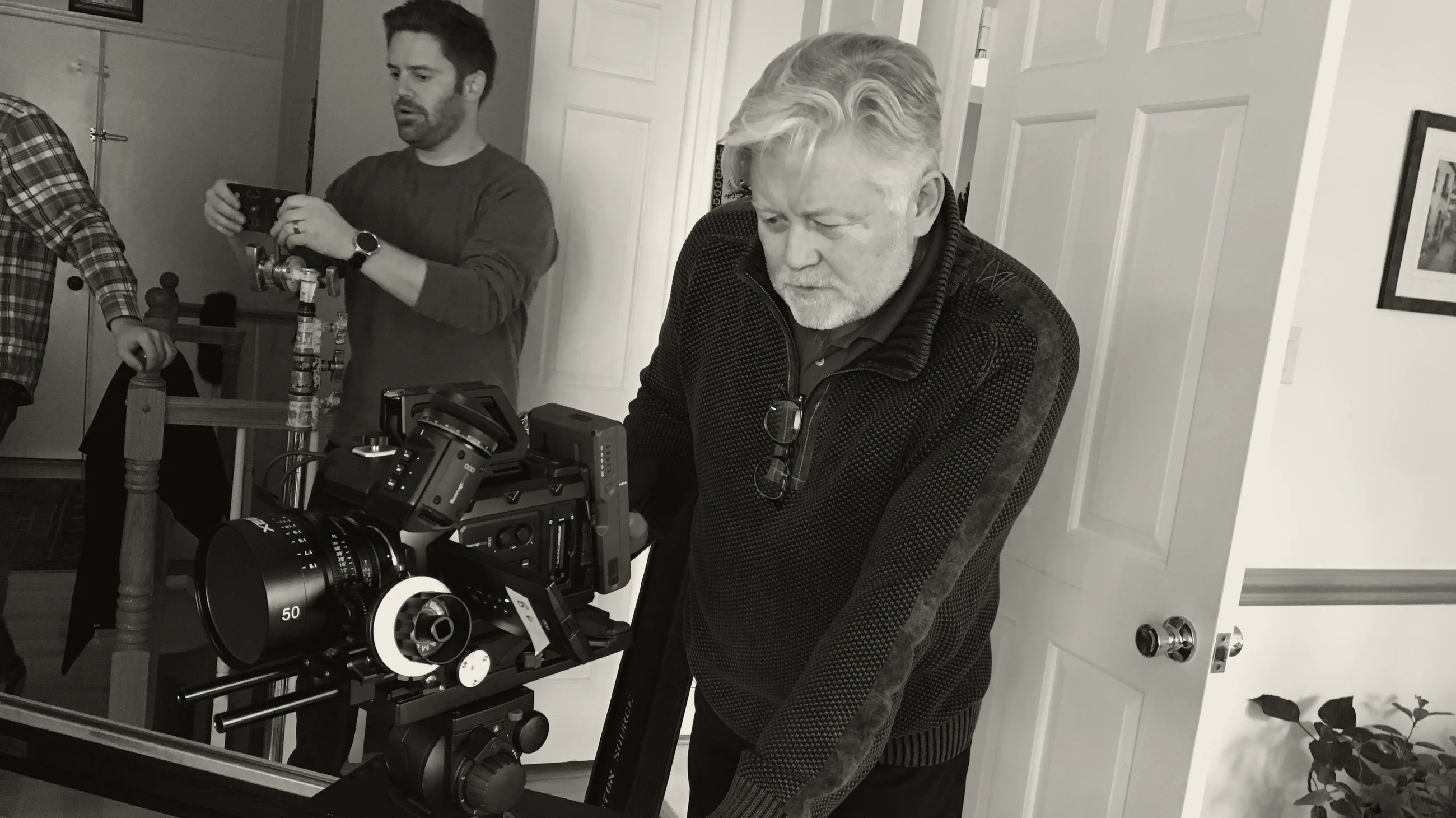 McKay Daines leaning over a camera on a slider, directing on the set of the documentary True Iran, with two crew members behind him.